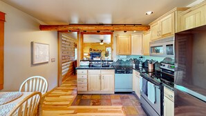 Una cocina con armarios de madera, una isla central, microondas, horno y lavavajillas.