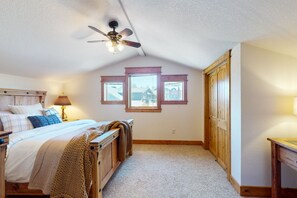 Une chambre à coucher avec un lit, un ventilateur de plafond, une fenêtre et une armoire en bois.