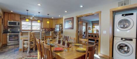 Una cocina amplia con armarios de madera, una mesa de comedor preparada para cuatro personas y lavadora y secadora integradas.