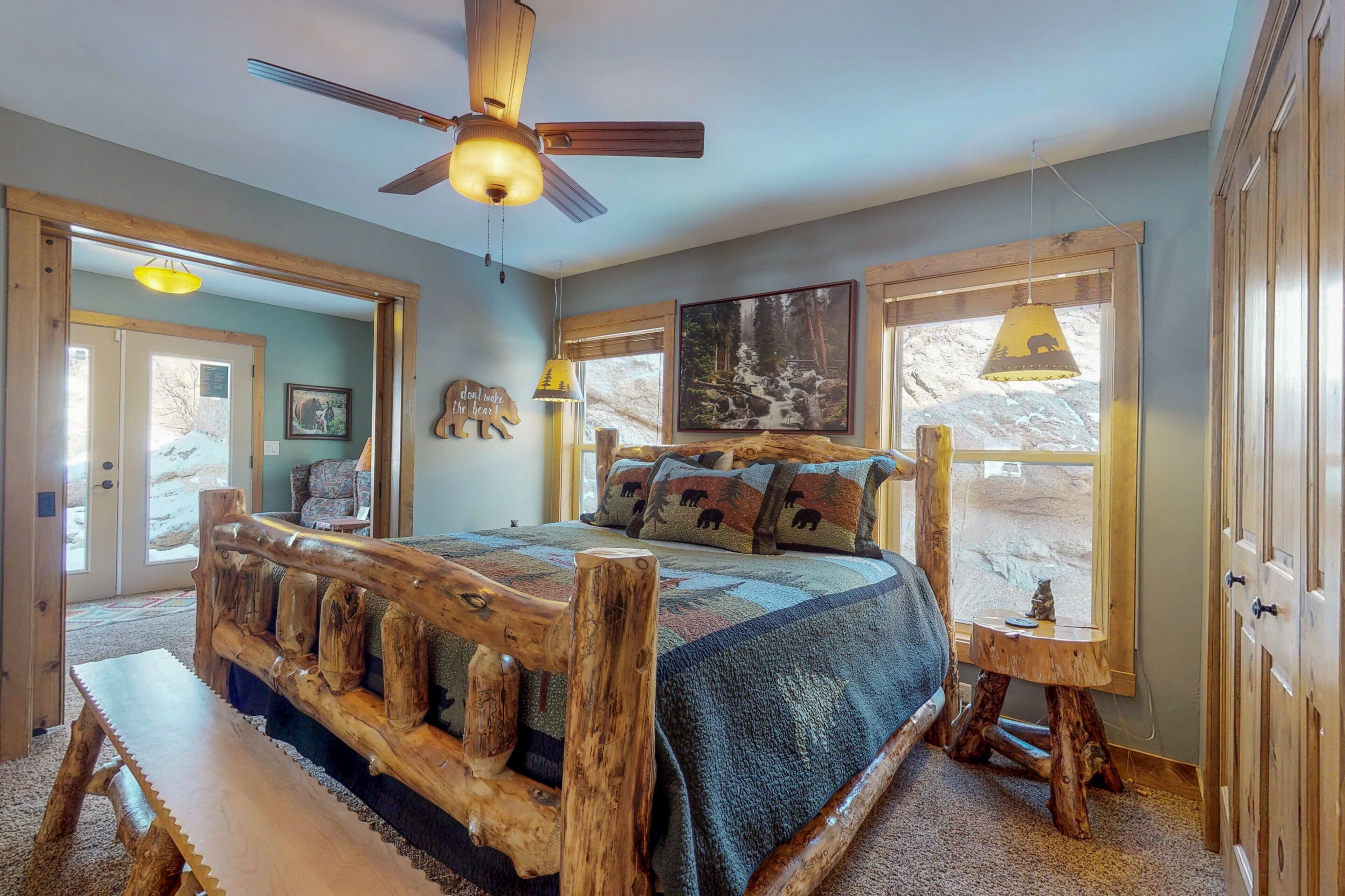 Ein Schlafzimmer mit einem Bettgestell aus Holz, einem Deckenventilator und einem großen Fenster mit Blick auf eine verschneite Landschaft.