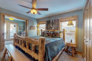 Ein Schlafzimmer mit einem Bettgestell aus Holz, einem Deckenventilator und einem großen Fenster mit Blick auf eine verschneite Landschaft.