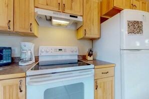 Eine Küche mit Holzausstattung, einem weißen Herd, einer Kaffeemaschine und einem Kühlschrank.