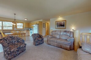 A living room with a leather sofa, a patterned armchair, and a dining area with wooden chairs and a table. - Wonderful Location With Full Kitchen, Furnished Deck & Mountain Views (Estes Park)