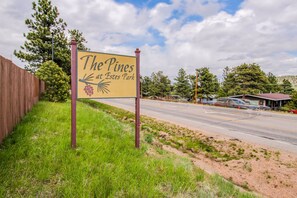 Schild für 'The Pines at Estes Park' mit freier Sicht auf eine Straße und umliegendes Grün.