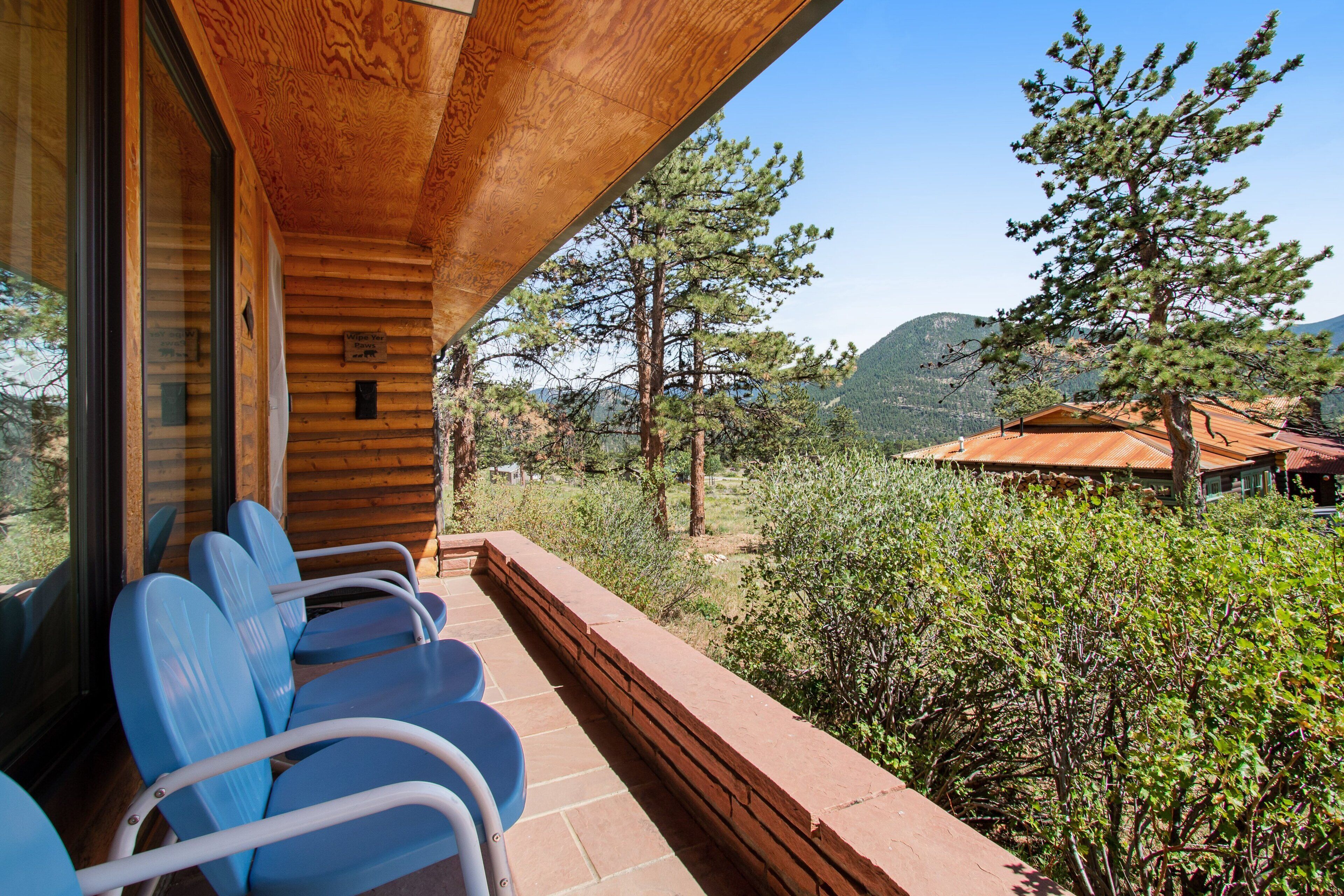 Une cabane en bois dotée d’un balcon avec un espace salon, d’un plafond en bois et offrant une vue sur la forêt et les montagnes environnantes.