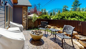 An outdoor patio with stone flooring, a fire pit, and metal chairs. - Luxurious Dog-friendly Townhome Near Lake Estes With Fantastic Views (Estes Park)