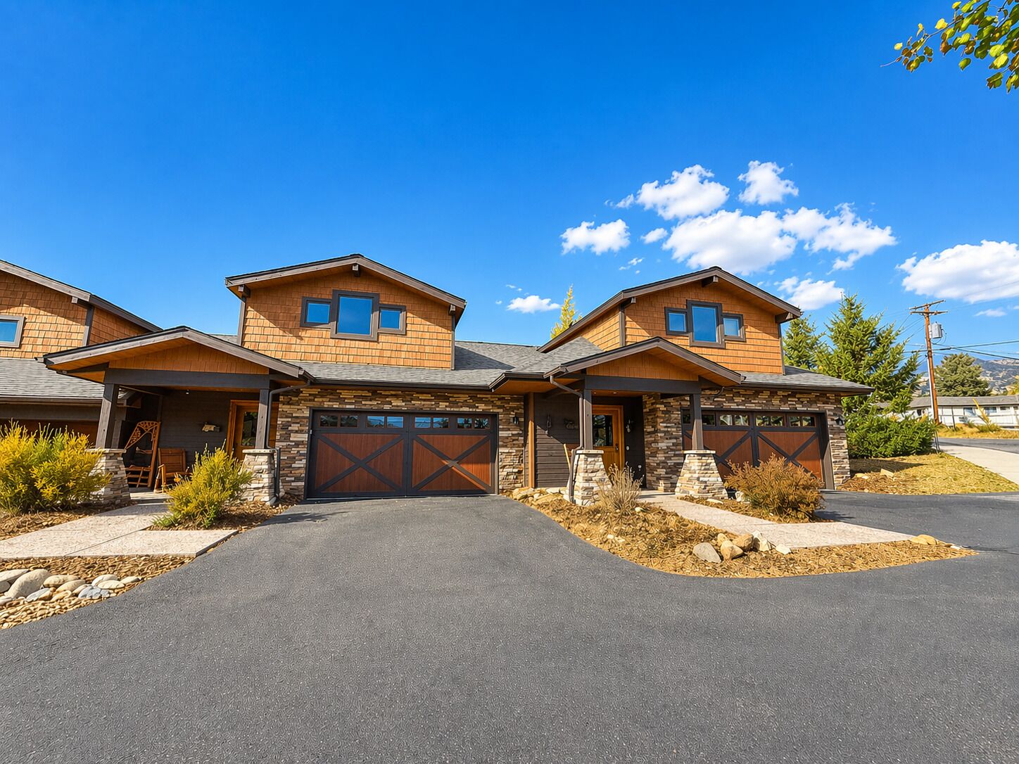 A modern two-story house with a stone facade, large garage doors, and a driveway.