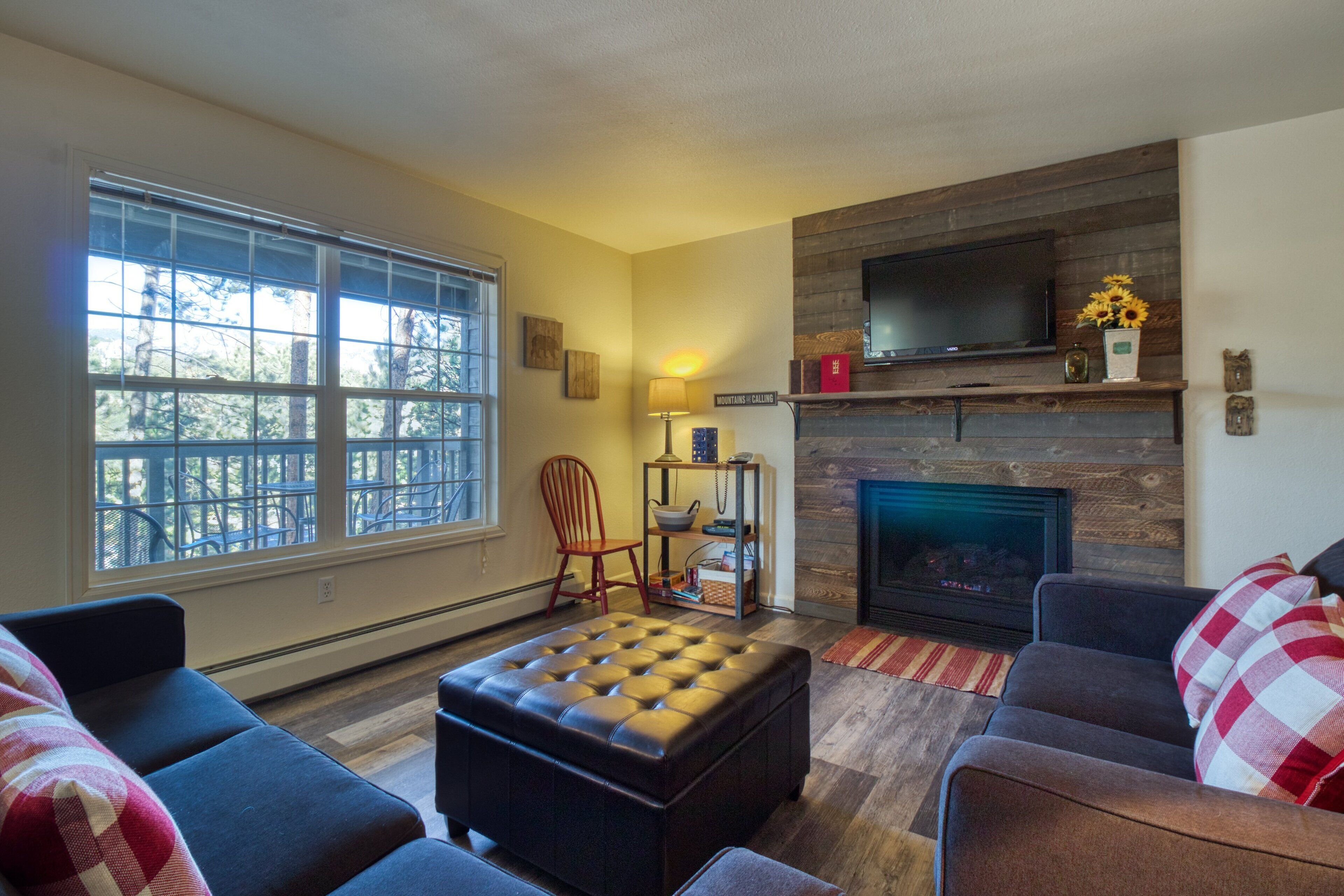 Una sala de estar con chimenea, televisor y un ventanal grande.