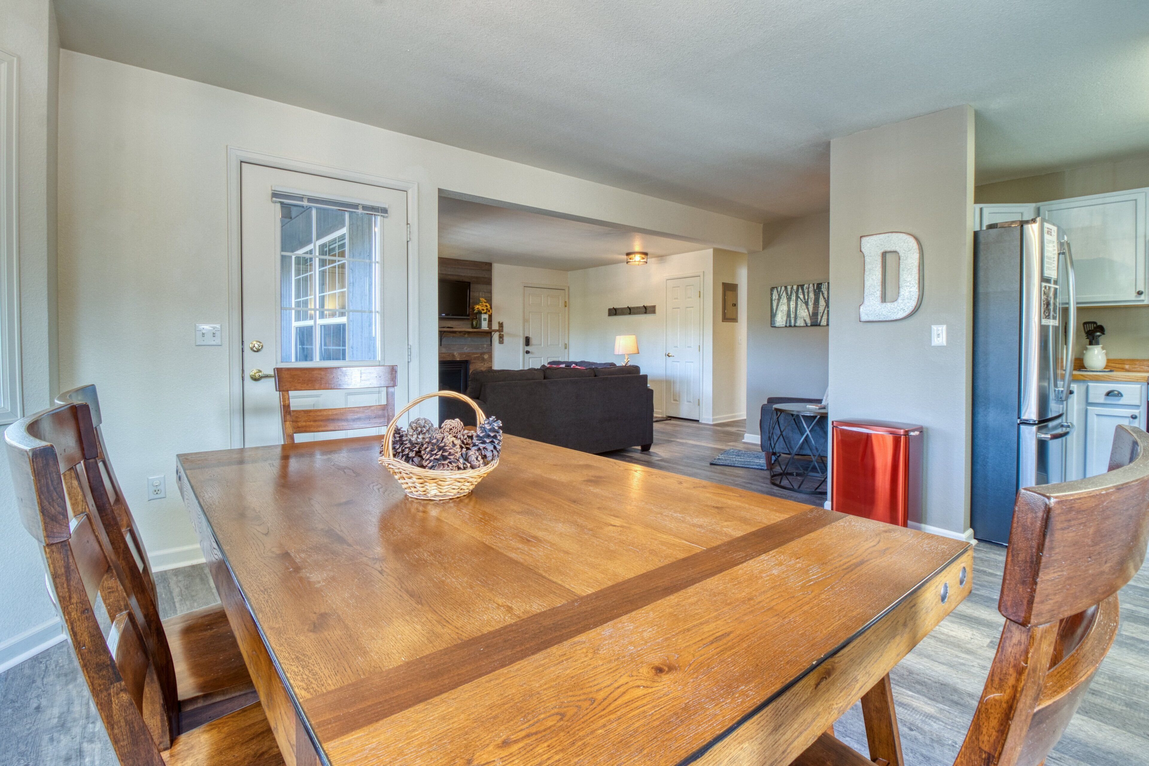 A dining area with a wooden table, chairs, and a basket of pinecones.