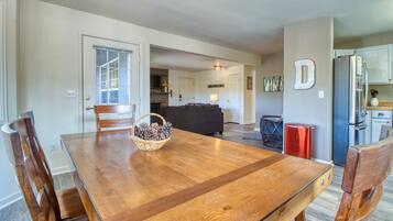 A dining area with a wooden table, chairs, and a basket of pinecones.