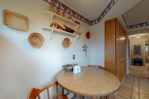 Ein Essbereich mit einem runden Holztisch, Stühlen, Regalen mit Dekoration und einer Wand mit Sternenornamenten.