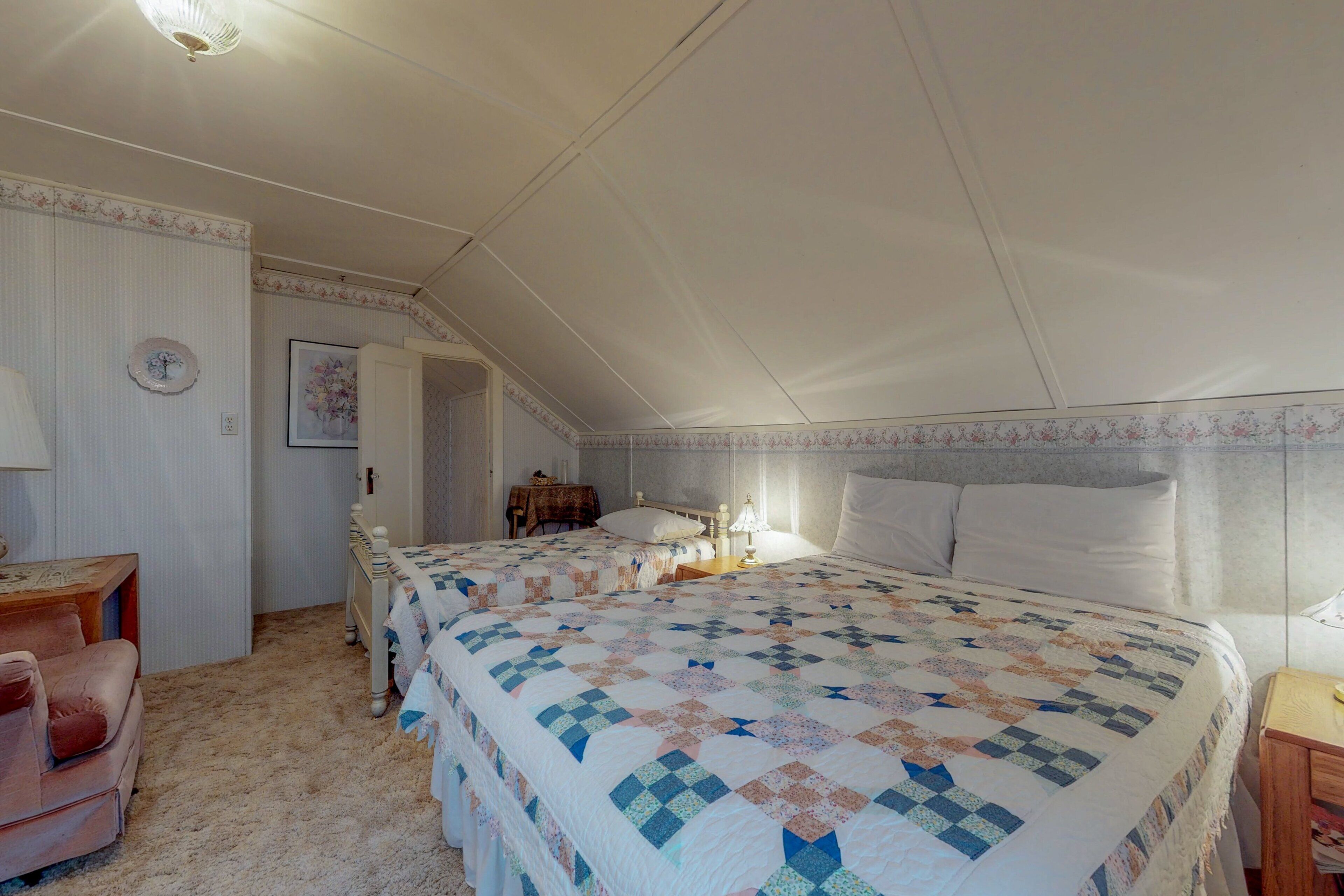 A bedroom with a large bed, a bedside table, a lamp, and a chair.