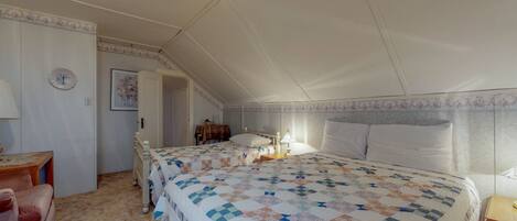 A bedroom with a large bed, a bedside table, a lamp, and a chair.
