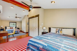 Ein Schlafzimmer mit Bett, Schreibtisch, Stuhl, Deckenventilator und einer Tür.