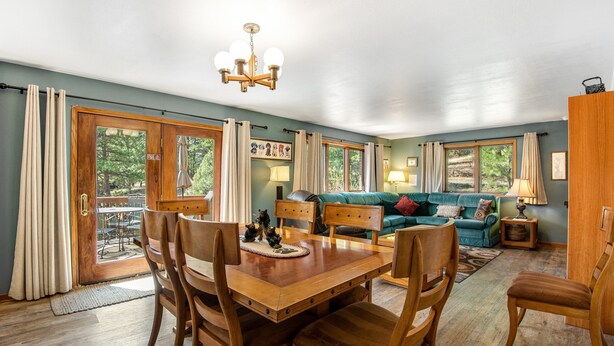 A dining area with a wooden table and chairs, a sofa, and a chandelier. - Dog-friendly, Mountain-view Home With Deck & Grill (Estes Park)