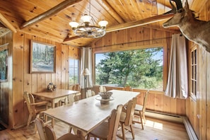 A wooden interior with a dining table, chairs, a chandelier, and a mounted animal head. - Cabin on 7 Acres With Glorious Mountain Views & Wood Fireplace (Estes Park)