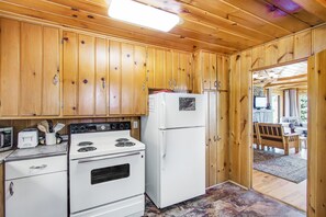 Eine Küche mit Holzausstattung, einem Herd, einem Kühlschrank und einer Mikrowelle.