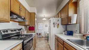 Una cocina con armarios de madera, una estufa de acero inoxidable, un refrigerador y un lavaplatos.