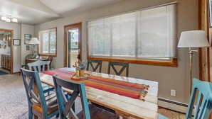 Un comedor con mesa de madera, sillas y una ventana con persianas.