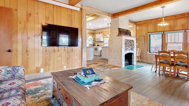 Ein Holzinterieur mit Fernseher, Kamin, Essbereich und K üche.