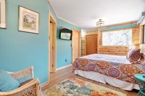 Ein Schlafzimmer mit Bett, Fernseher, Stuhl und einem Fenster mit Blick.