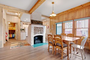 A cozy room with a fireplace, wooden furniture, and a dining area. - Charming Cabin With Full Kitchen, Furnished Deck, & Incredible Views (Estes Park)