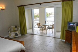 Ein Hotelzimmer mit Bett, Fernseher, Sessel, Tisch und einem Balkon mit Blick.