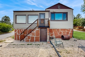 A two-story house with a stone facade, a wooden staircase, and a small porch. - Cozy Cottage With Grill Near River and Downtown (Estes Park)