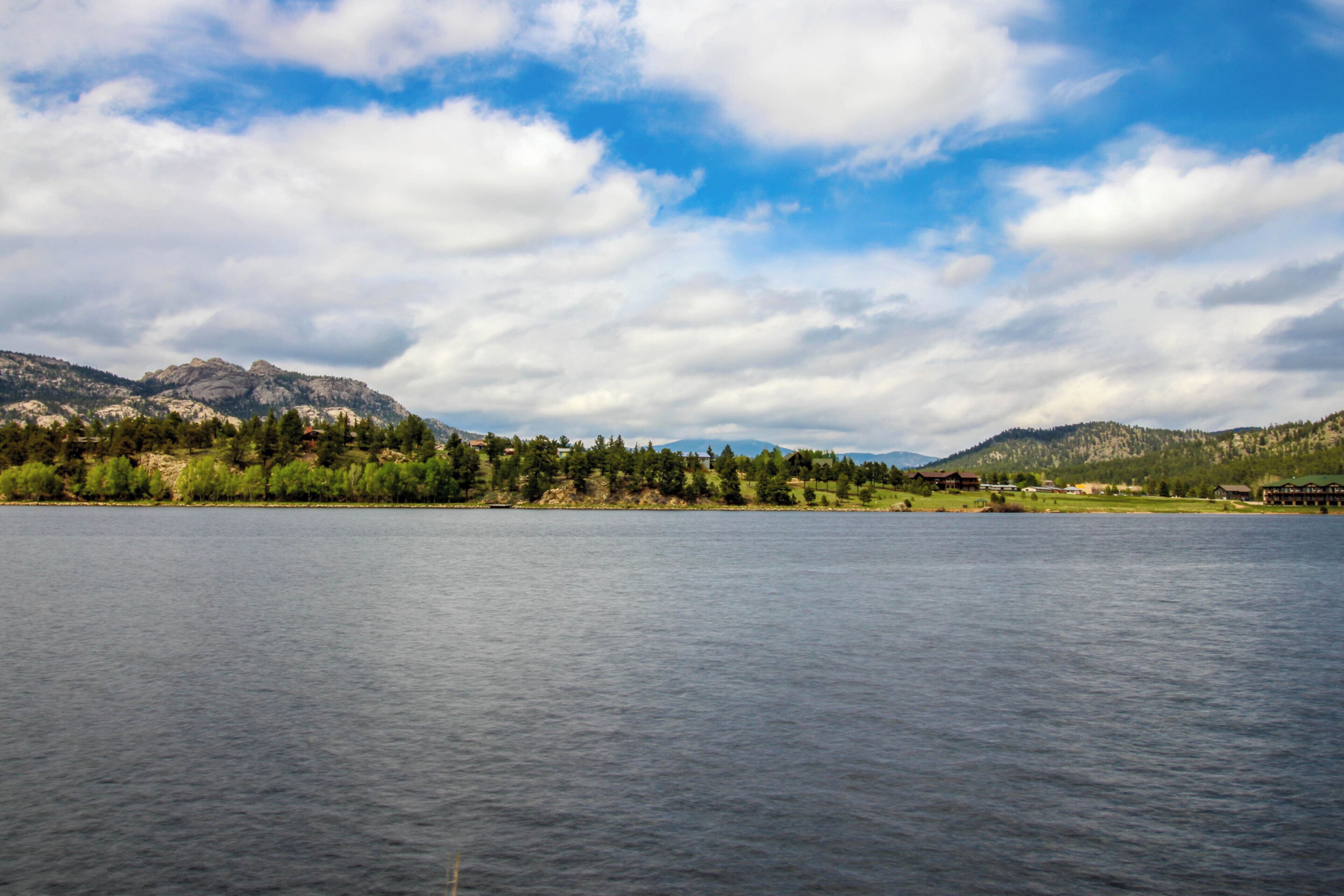 Un lago con montañas al fondo y cielo despejado.