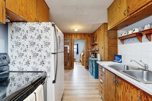 Eine Küche mit Holzausstattung, einem Kühlschrank, einem Herd und einem Spülbecken.