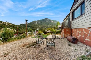 A gravel patio with outdoor furniture and a rustic barrel. - Cozy Cottage With Grill Near River and Downtown (Estes Park)