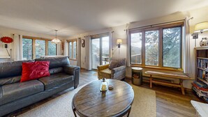 A living room with a sofa, a round coffee table, a bench, and a bookshelf. - Inviting Cabin With Stellar Panoramic Rocky Mountain Views (Estes Park)