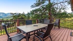 A deck with a table and chairs, overlooking a mountainous landscape. - Inviting Cabin With Stellar Panoramic Rocky Mountain Views (Estes Park)