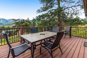 A deck with a table and chairs, overlooking a mountainous landscape. - Inviting Cabin With Stellar Panoramic Rocky Mountain Views (Estes Park)