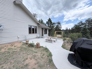 Ein Haus mit überdachter Terrasse, Schaukel und Grill.
