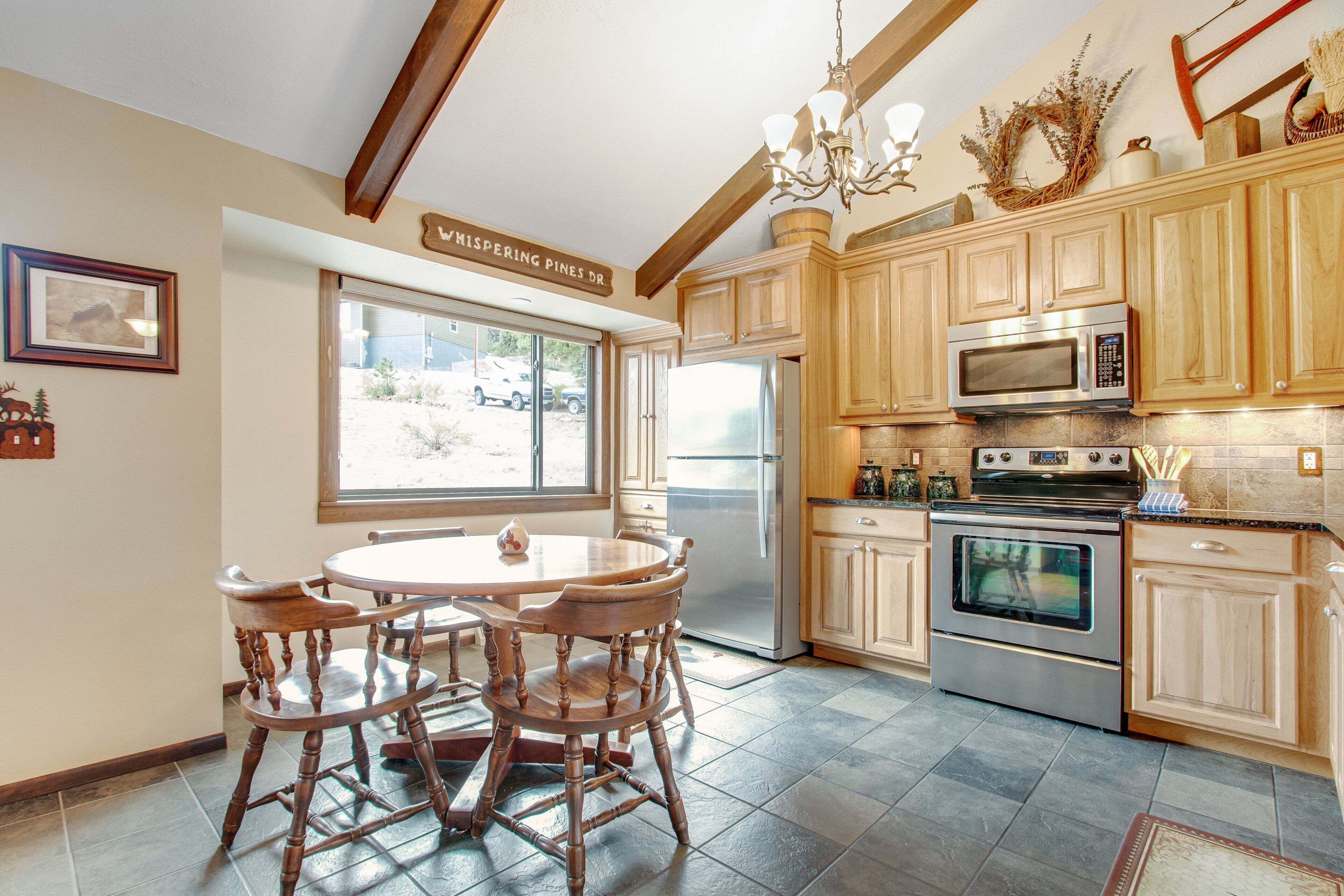 A kitchen with wooden cabinets, a dining table with chairs, a refrigerator, a microwave, and an oven.