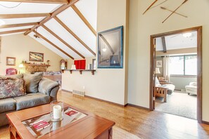 Un salon spacieux avec un plafond en bois, une cheminée, un canapé et une table basse.