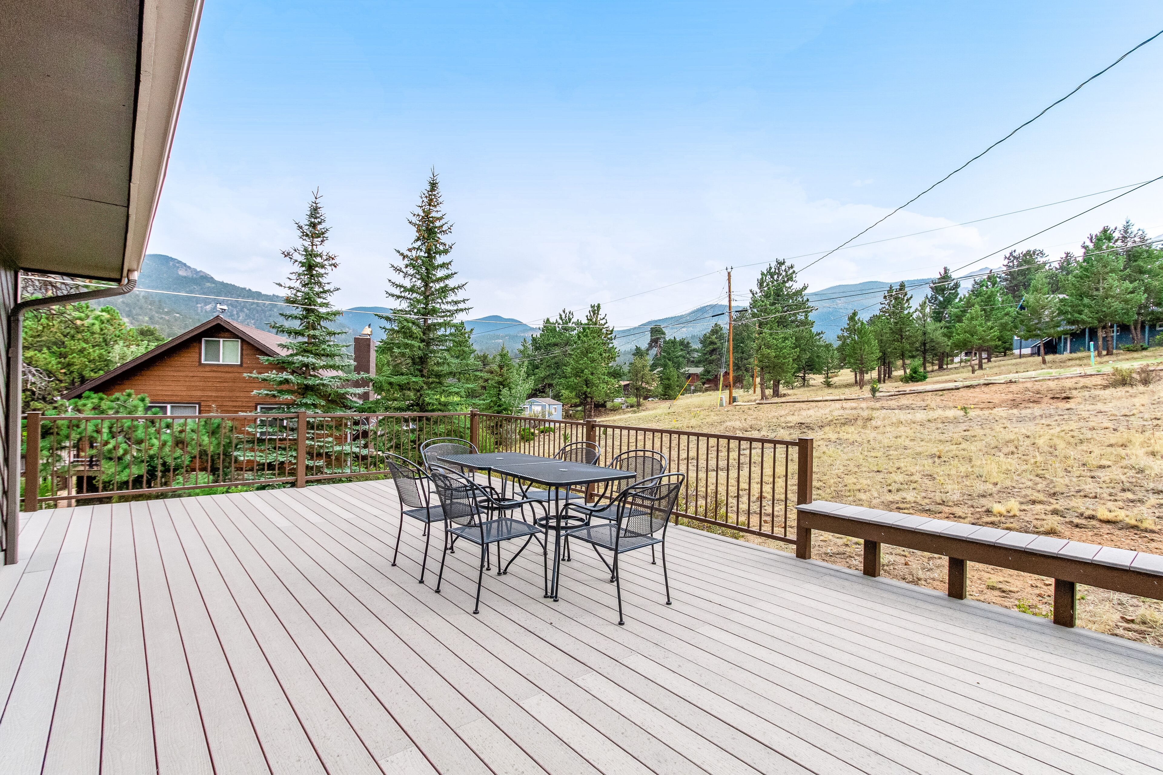 Une terrasse en bois avec une table et des chaises, offrant une vue sur un paysage montagneux.