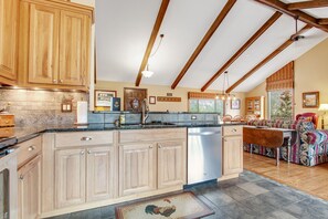 A spacious kitchen with wooden cabinets, a central island, and a dining area with a patterned sofa. - Three BR With Epic Mountain Views and Huge Deck! (Estes Park)