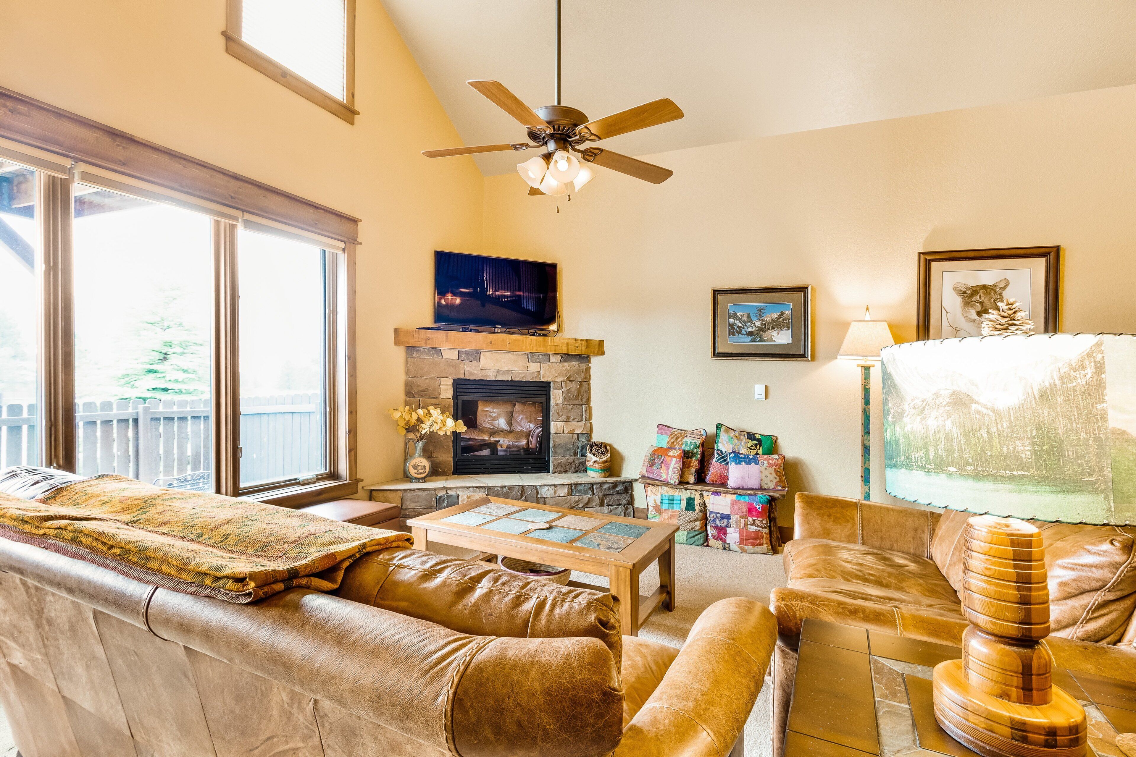 A living room with a fireplace, leather sofas, a coffee table, and a television.