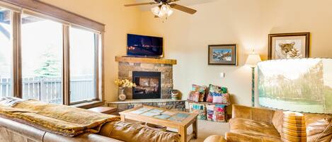 A living room with a fireplace, leather sofas, a coffee table, and a television.