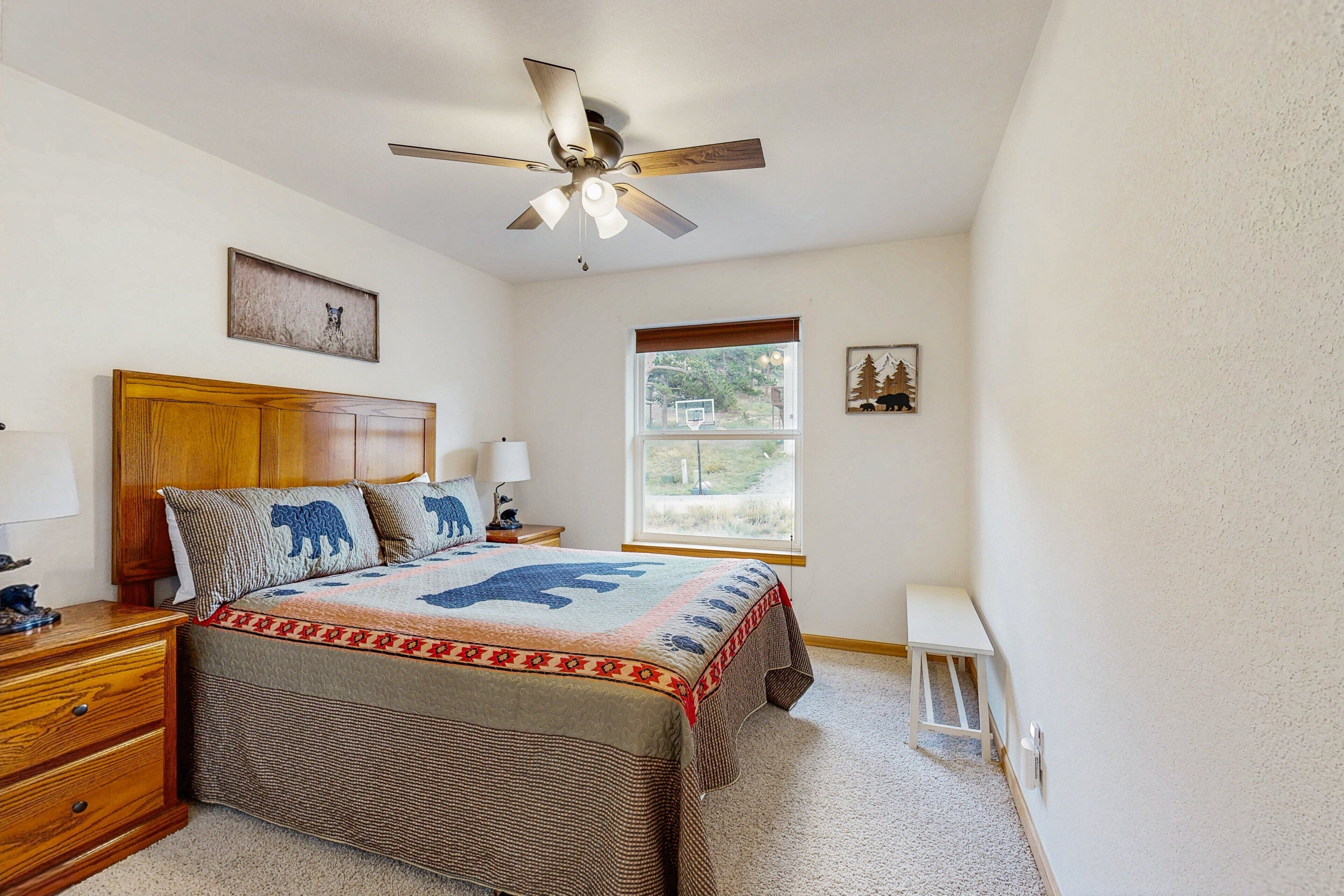 A bedroom with a bed, a ceiling fan, a window, and a nightstand.
