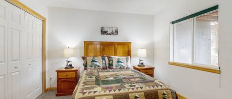 A bedroom with a bed, two bedside tables, a headboard, a wall-mounted picture, and a window.