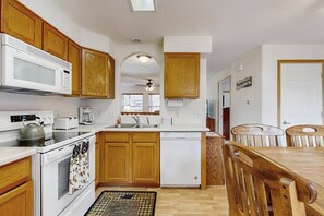 A kitchen with wooden cabinets, a microwave, an oven, a dishwasher, and a dining table with chairs. - Conveniently Located Home w/ Full Kitchen, Deck & Mountain Views (Estes Park)