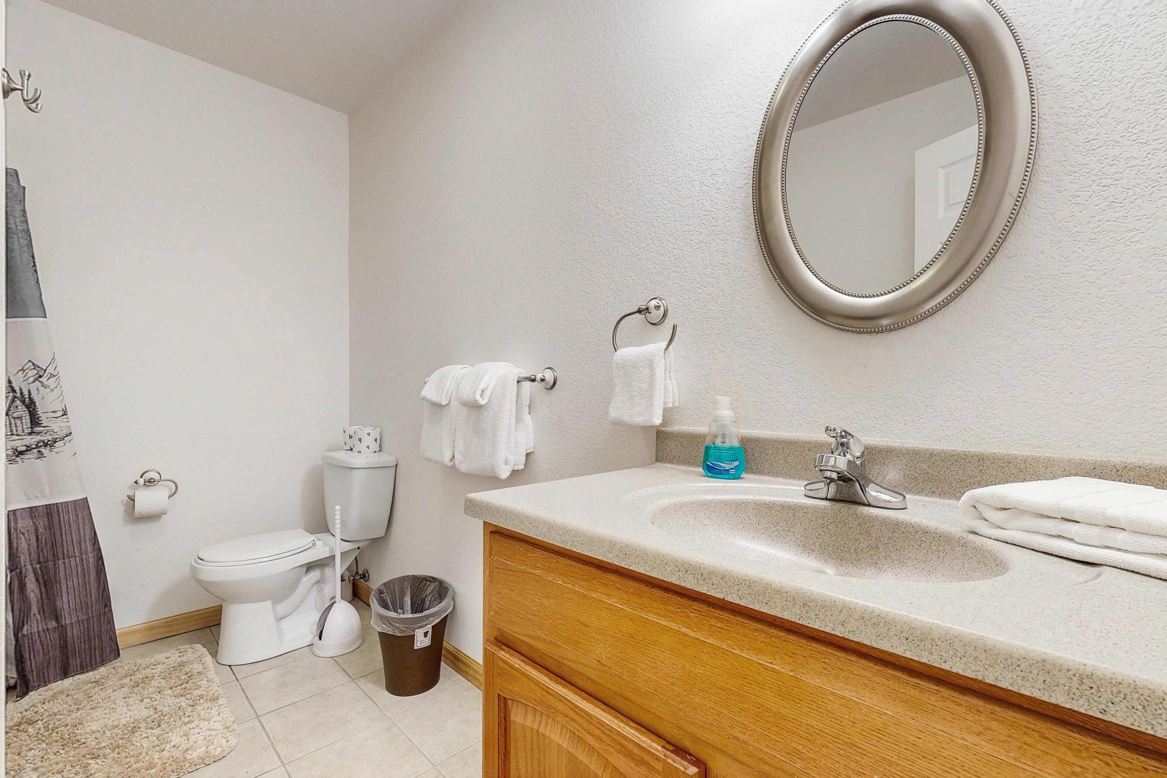 A bathroom with a toilet, sink, mirror, and towels.