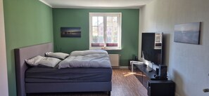 A bedroom with a bed, a window, a TV, and a radiator. - Coach house at the Amber Castle (Kuhlen-Wendorf)