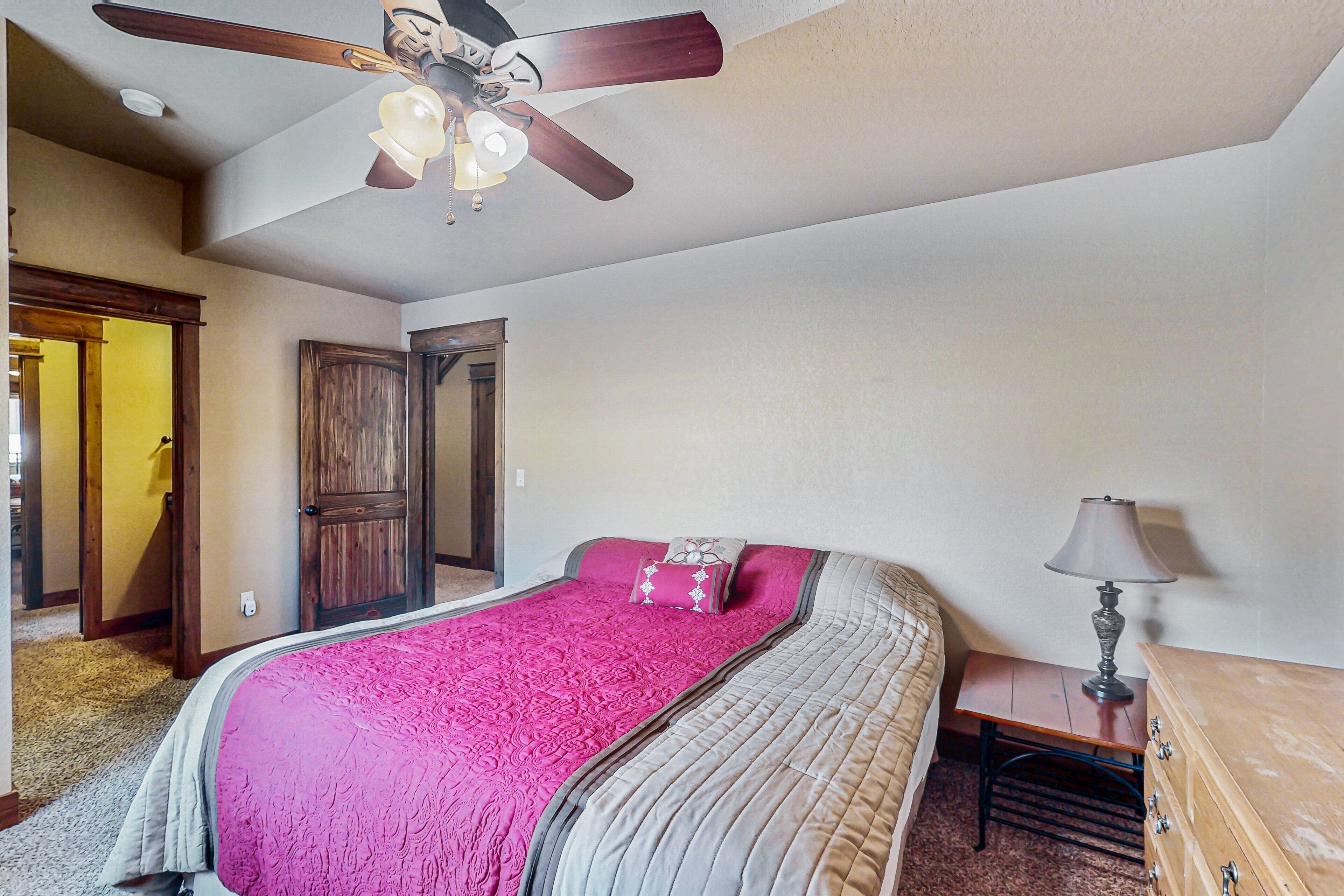 A bedroom with a bed, a ceiling fan, a nightstand, and a dresser.