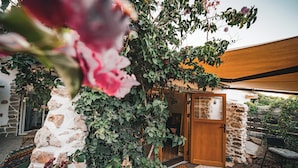A stone wall with climbing plants, a wooden door, and a wooden deck.
