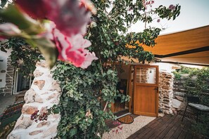 A stone wall with climbing plants, a wooden door, and a wooden deck.