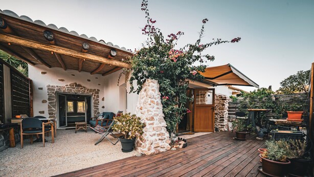 A patio with wooden flooring, stone walls, and potted plants.